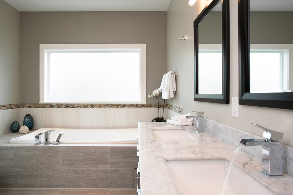 Diseño de cuarto de baño actual con lavabo bajoencimera, bañera encastrada, sanitario de una pieza, baldosas y/o azulejos beige y baldosas y/o azulejos de piedra