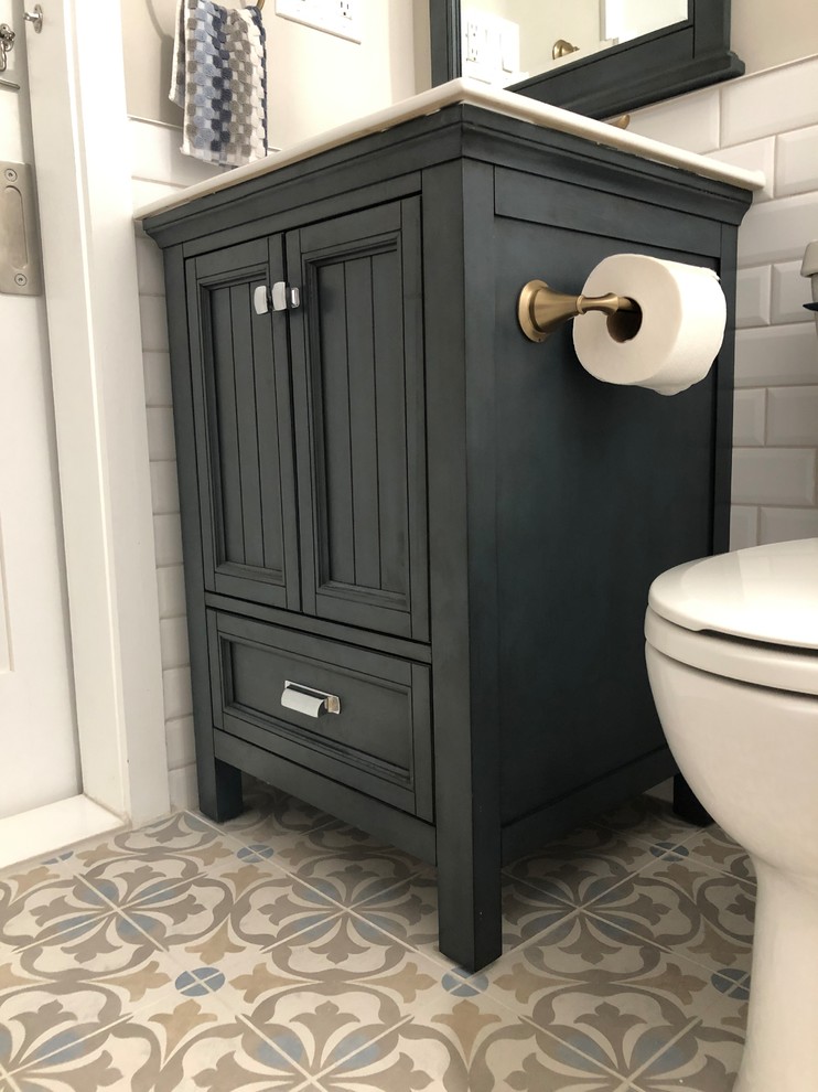 This is an example of a small modern ensuite bathroom in Philadelphia with freestanding cabinets, blue cabinets, an alcove bath, a shower/bath combination, a two-piece toilet, white tiles, ceramic tiles, beige walls, ceramic flooring, an integrated sink, solid surface worktops, beige floors, a shower curtain and white worktops.