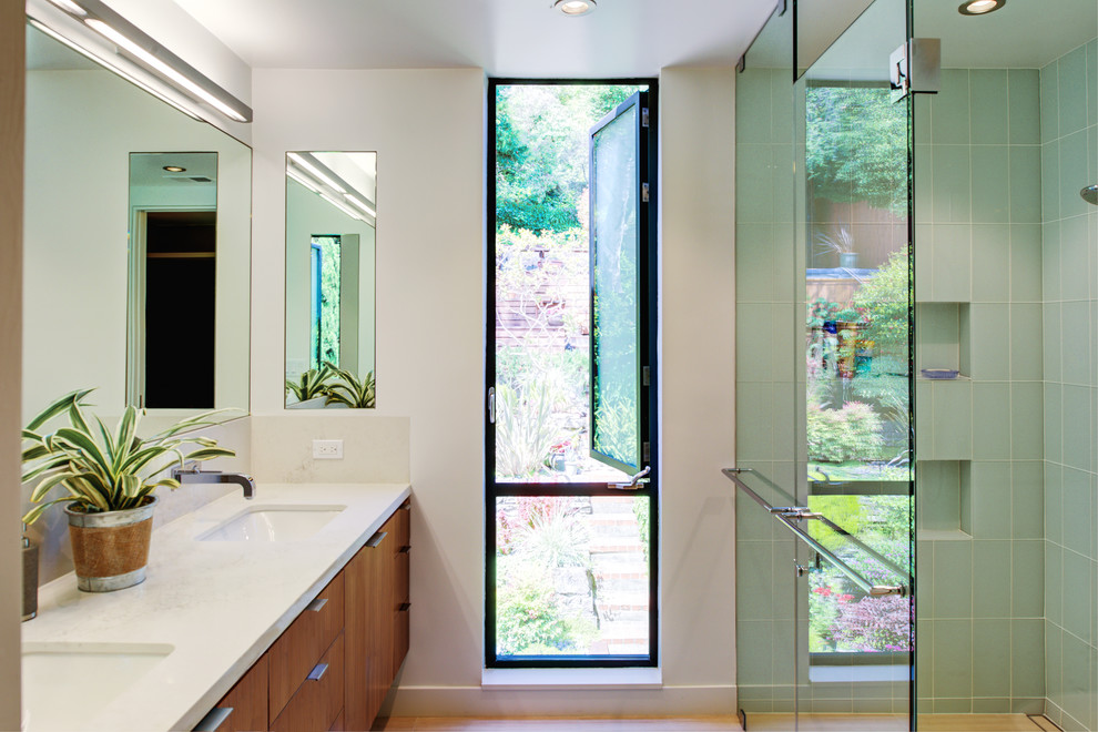 Small trendy master glass tile and green tile porcelain tile and beige floor corner shower photo in San Francisco with flat-panel cabinets, medium tone wood cabinets, white walls, an undermount sink, quartz countertops, a hinged shower door and white countertops