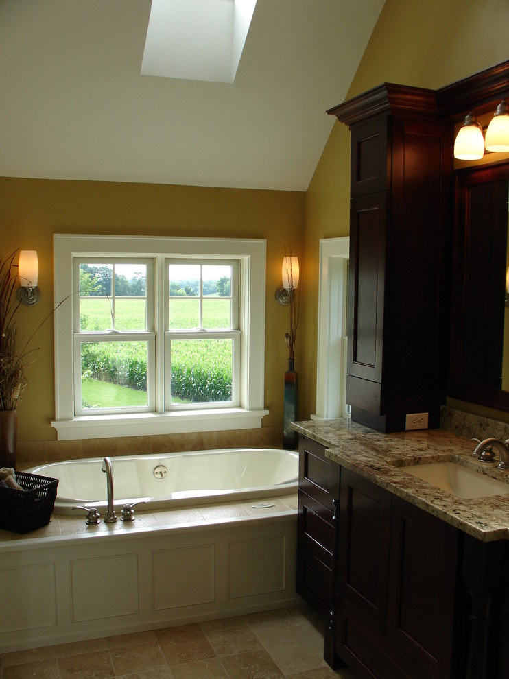 Inspiration for a medium sized traditional ensuite bathroom in Milwaukee with recessed-panel cabinets, dark wood cabinets, a built-in bath, beige tiles, porcelain tiles, beige walls, porcelain flooring, a submerged sink, granite worktops and beige floors.