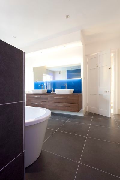 Стильный дизайн: огромная главная ванная комната в современном стиле с настольной раковиной, плоскими фасадами, фасадами цвета дерева среднего тона, стеклянной столешницей, отдельно стоящей ванной, двойным душем, раздельным унитазом, коричневой плиткой, керамогранитной плиткой, синими стенами и полом из керамогранита - последний тренд