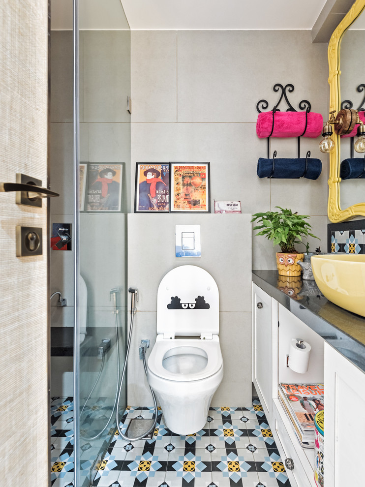 ムンバイにあるエクレクティックスタイルのおしゃれな浴室 (バリアフリー、壁掛け式トイレ、グレーの壁、ベッセル式洗面器、マルチカラーの床) の写真