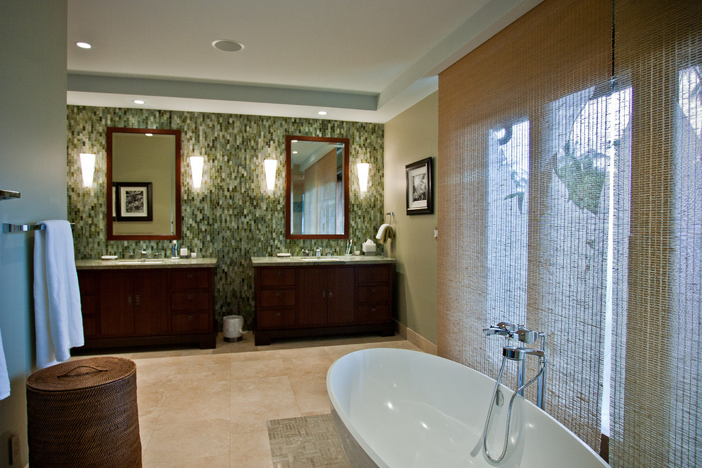 Example of a large island style master green tile and glass tile ceramic tile and beige floor freestanding bathtub design in Hawaii with furniture-like cabinets, dark wood cabinets, beige walls, an undermount sink and granite countertops