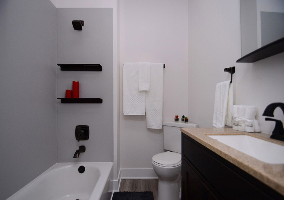 Inspiration pour une petite salle de bain principale minimaliste avec un placard à porte shaker, des portes de placard noires, une baignoire en alcôve, un combiné douche/baignoire, WC séparés, un mur blanc, un sol en vinyl, un lavabo encastré, un plan de toilette en surface solide, un sol gris, une cabine de douche avec un rideau et un plan de toilette beige.