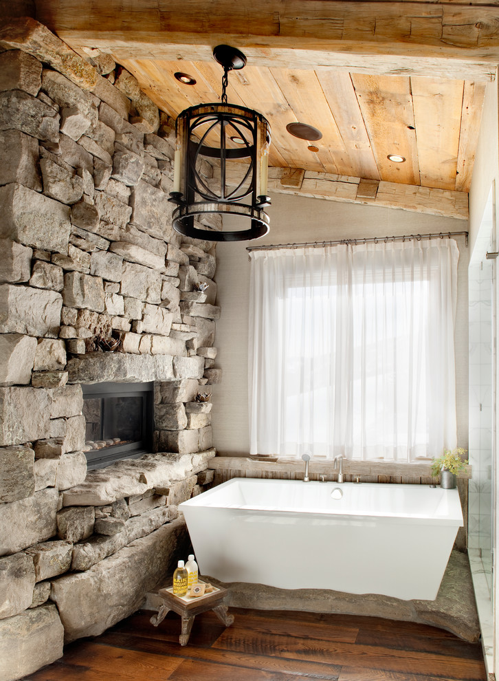Inspiration for a rustic stone slab medium tone wood floor freestanding bathtub remodel in Other with beige walls and marble countertops