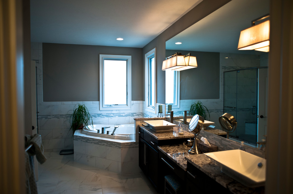 Réalisation d'une grande salle de bain principale tradition en bois foncé avec une vasque, un placard à porte plane, un plan de toilette en granite, une baignoire d'angle, une douche d'angle, un carrelage gris et un mur beige.