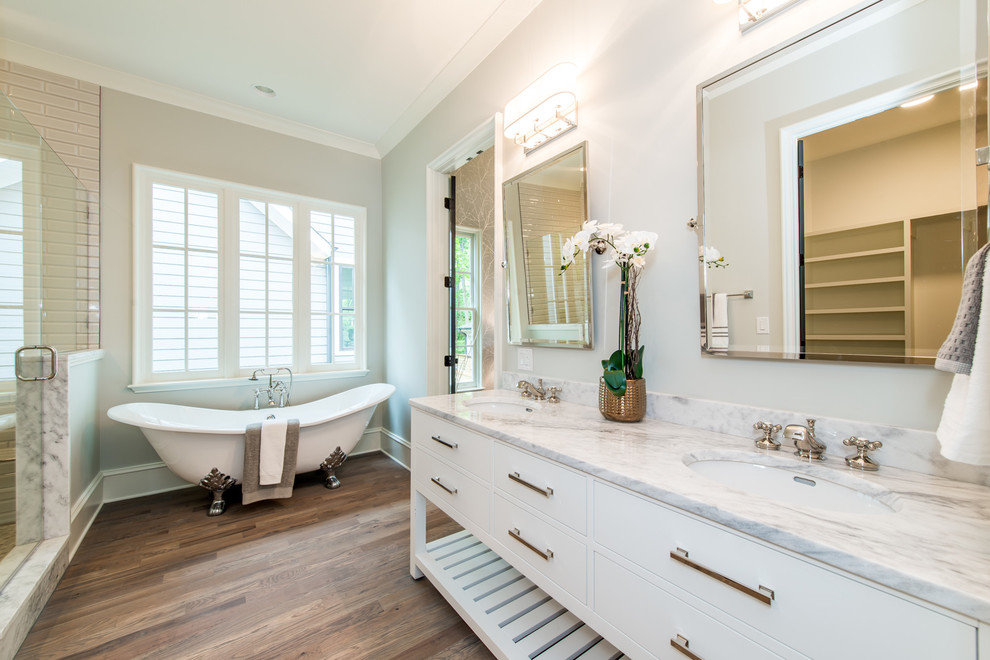 Стильный дизайн: главная ванная комната среднего размера в классическом стиле с ванной на ножках, белой плиткой, бежевыми стенами, паркетным полом среднего тона, коричневым полом и душем с распашными дверями - последний тренд