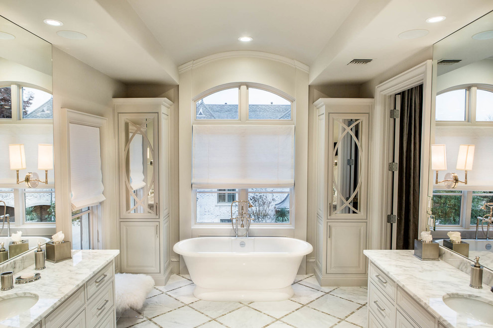 Пример оригинального дизайна: большая главная ванная комната в стиле неоклассика (современная классика) с врезной раковиной, фасадами с утопленной филенкой, белыми фасадами, мраморной столешницей, отдельно стоящей ванной, белой плиткой, белыми стенами и мраморным полом