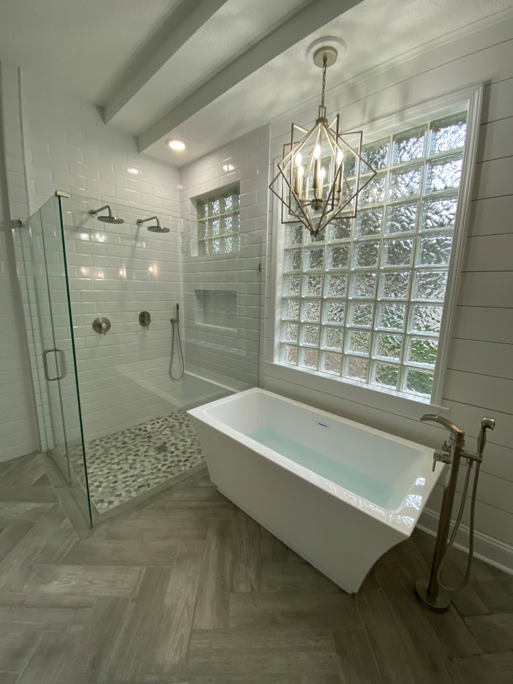 Источник вдохновения для домашнего уюта: большая главная ванная комната в стиле модернизм с фасадами в стиле шейкер, белыми фасадами, отдельно стоящей ванной, двойным душем, унитазом-моноблоком, белой плиткой, плиткой кабанчик, серыми стенами, полом из плитки под дерево, настольной раковиной, столешницей из гранита, серым полом, душем с распашными дверями, белой столешницей, нишей, тумбой под две раковины, напольной тумбой, многоуровневым потолком и стенами из вагонки
