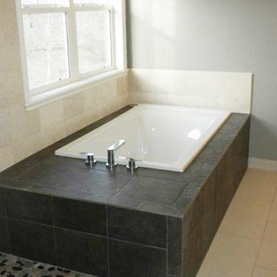 This is an example of a medium sized traditional ensuite bathroom in Denver with recessed-panel cabinets, dark wood cabinets, a built-in bath, a one-piece toilet, beige tiles, beige walls, a built-in sink, granite worktops, vinyl flooring, brown floors, a corner shower, a hinged door and stone tiles.