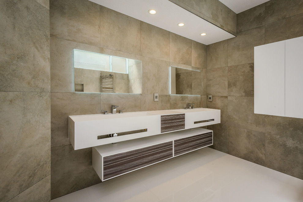 Exemple d'une grande salle de bain principale moderne en bois brun avec un lavabo intégré, un placard à porte plane, un plan de toilette en surface solide, une baignoire indépendante, une douche à l'italienne, WC suspendus, un carrelage beige, un carrelage de pierre et un mur beige.