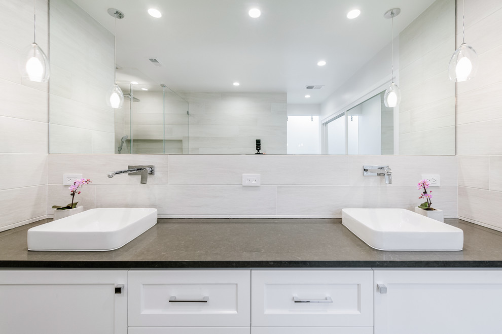 Large contemporary ensuite bathroom in Los Angeles with shaker cabinets, white cabinets, a freestanding bath, black tiles, porcelain tiles, white walls, porcelain flooring, a vessel sink, engineered stone worktops, grey floors and black worktops.