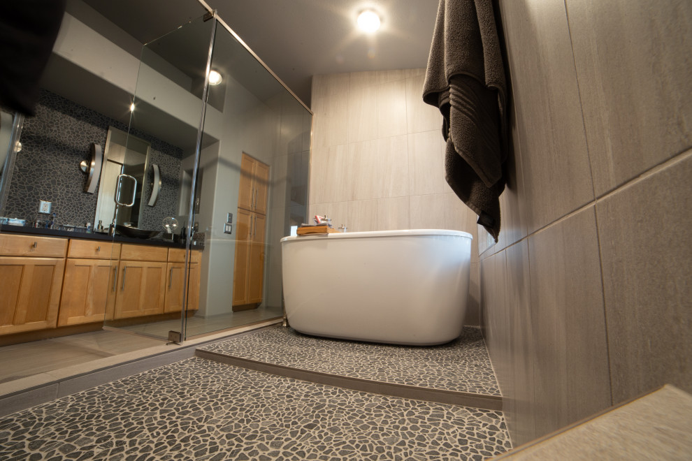 Идея дизайна: огромная главная ванная комната в стиле модернизм с отдельно стоящей ванной, душевой комнатой, серой плиткой, галечной плиткой, серыми стенами, полом из керамогранита, настольной раковиной, серым полом, душем с раздвижными дверями, тумбой под две раковины и встроенной тумбой
