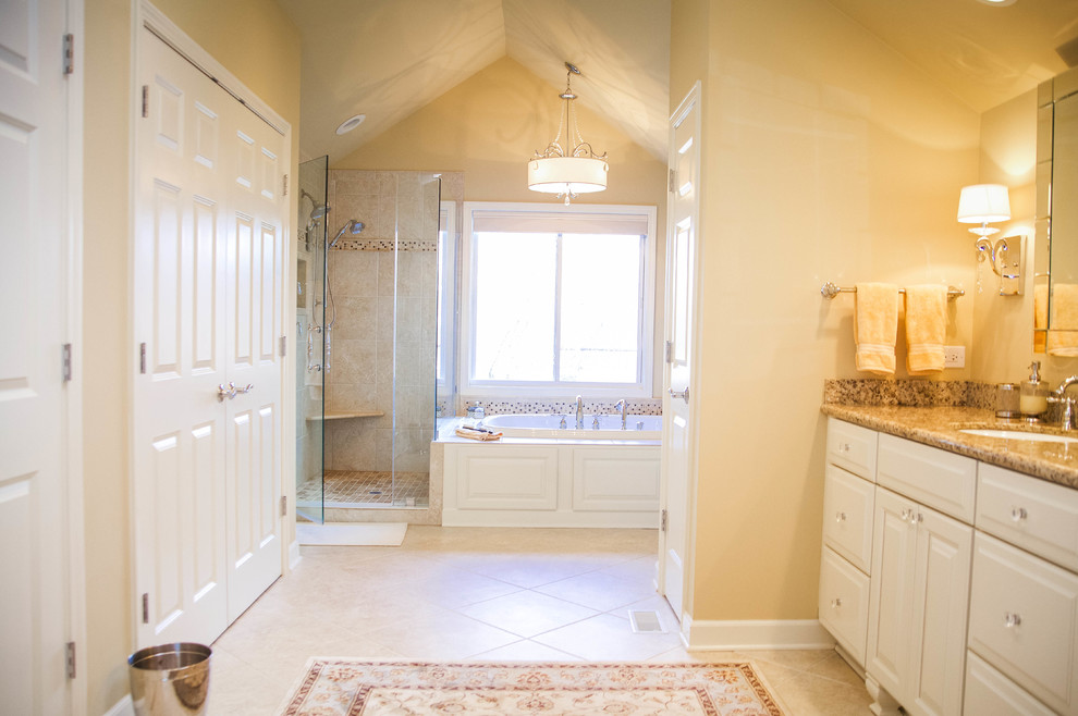 Exemple d'une grande salle de bain principale chic avec un lavabo encastré, un placard avec porte à panneau surélevé, des portes de placard beiges, un plan de toilette en granite, une baignoire posée, une douche d'angle, WC séparés, un carrelage beige, un carrelage de pierre, un mur jaune et un sol en carrelage de céramique.