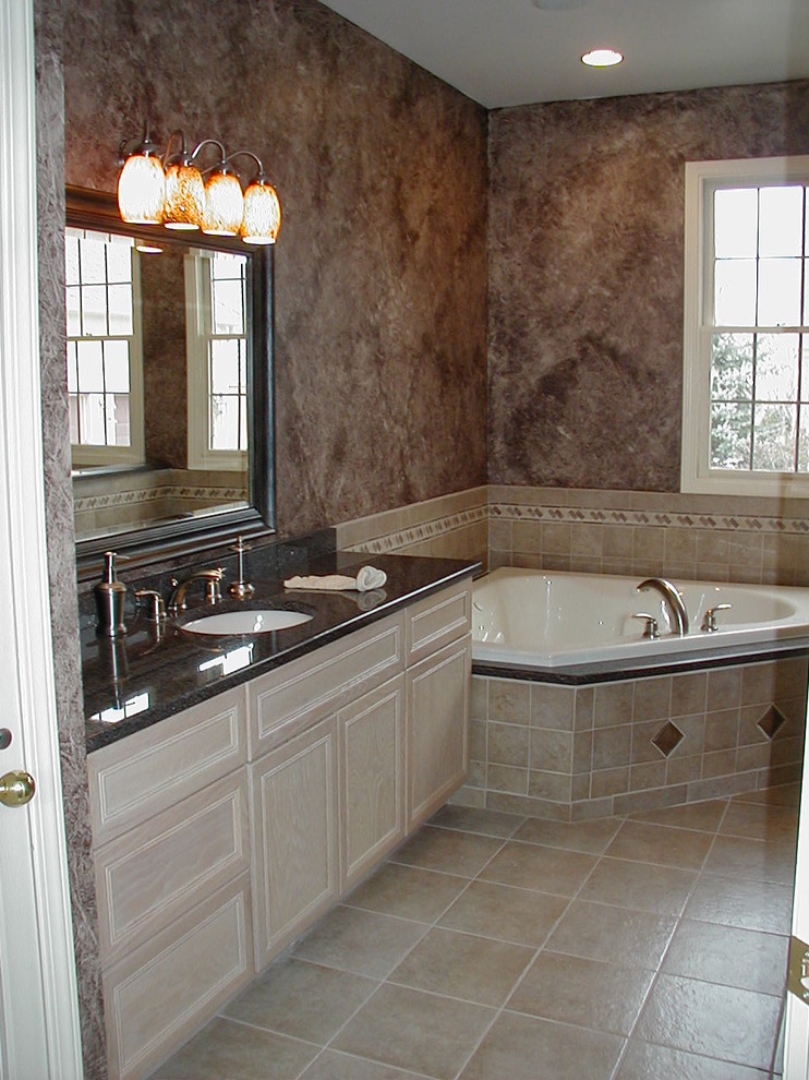 This is an example of a medium sized mediterranean ensuite bathroom in Detroit with light wood cabinets, a corner bath, a walk-in shower, beige tiles, ceramic tiles, ceramic flooring, granite worktops, raised-panel cabinets, a two-piece toilet, beige walls and a submerged sink.