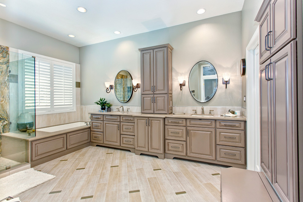 Immagine di una grande stanza da bagno chic con ante con bugna sagomata, vasca sottopiano e pareti grigie