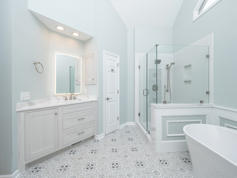 Idée de décoration pour une grande salle de bain principale tradition avec des portes de placard grises, une baignoire indépendante, un sol en carrelage de porcelaine, un lavabo encastré, un plan de toilette en quartz modifié, un placard à porte shaker, une douche d'angle, un carrelage blanc, des carreaux de céramique, un mur bleu, un sol gris, une cabine de douche à porte battante et un plan de toilette blanc.