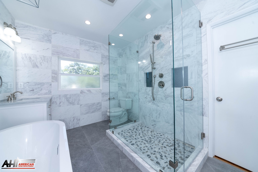 Идея дизайна: большая главная ванная комната в стиле модернизм с фасадами в стиле шейкер, серыми фасадами, отдельно стоящей ванной, душем без бортиков, унитазом-моноблоком, черной плиткой, плиткой мозаикой, белыми стенами, мраморным полом, мраморной столешницей, серым полом, душем с распашными дверями, белой столешницей, напольной тумбой и многоуровневым потолком