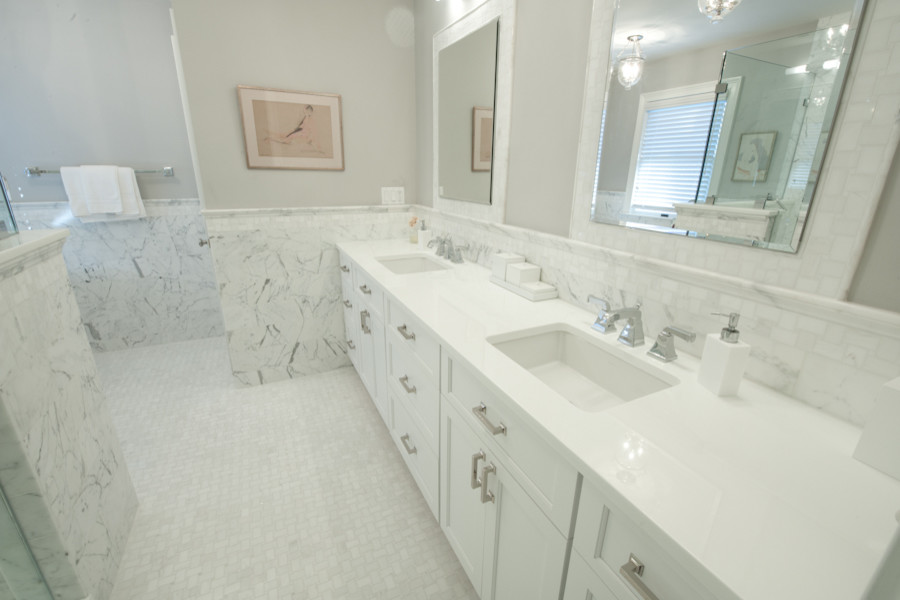 Идея дизайна: ванная комната в стиле неоклассика (современная классика) с врезной раковиной, фасадами в стиле шейкер, белыми фасадами, стеклянной столешницей, душем над ванной, унитазом-моноблоком, белой плиткой и каменной плиткой