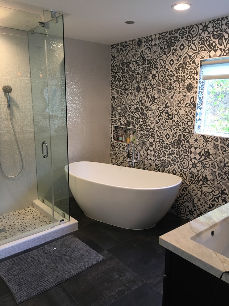 Modern inredning av ett stort en-suite badrum, med luckor med upphöjd panel, ett fristående badkar, våtrum, en vägghängd toalettstol, svart och vit kakel, porslinskakel, klinkergolv i keramik, ett nedsänkt handfat, bänkskiva i kvartsit och grått golv