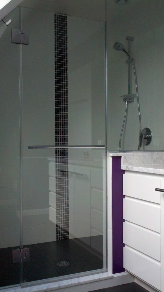 Modern inredning av ett litet en-suite badrum, med ett undermonterad handfat, släta luckor, vita skåp, marmorbänkskiva, en dusch i en alkov, en toalettstol med separat cisternkåpa, svart kakel, tunnelbanekakel, lila väggar och travertin golv