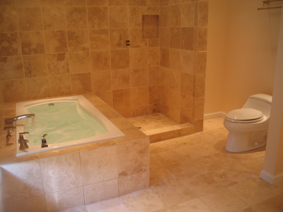 Foto di una stanza da bagno padronale minimal di medie dimensioni con vasca da incasso, doccia alcova, WC monopezzo, piastrelle beige, piastrelle in pietra, pareti beige e pavimento con piastrelle a mosaico