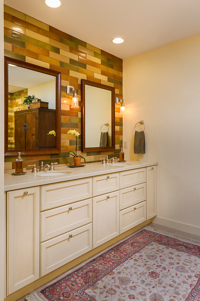 На фото: главная ванная комната в классическом стиле с фасадами с утопленной филенкой, желтыми фасадами, душем без бортиков, разноцветной плиткой, керамической плиткой, желтыми стенами, полом из керамогранита, врезной раковиной и столешницей из известняка с