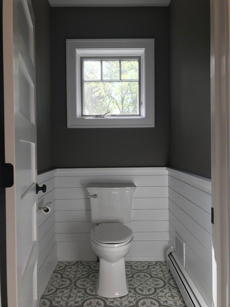 This is an example of a medium sized contemporary cloakroom in New York with raised-panel cabinets, white cabinets, a two-piece toilet, grey tiles, porcelain tiles, brown walls, ceramic flooring, a submerged sink, multi-coloured floors and beige worktops.
