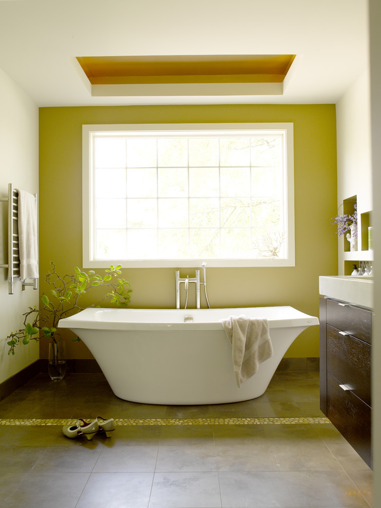 Aménagement d'une salle de bain contemporaine en bois foncé avec un placard à porte plane, une baignoire indépendante, un mur vert et un sol marron.