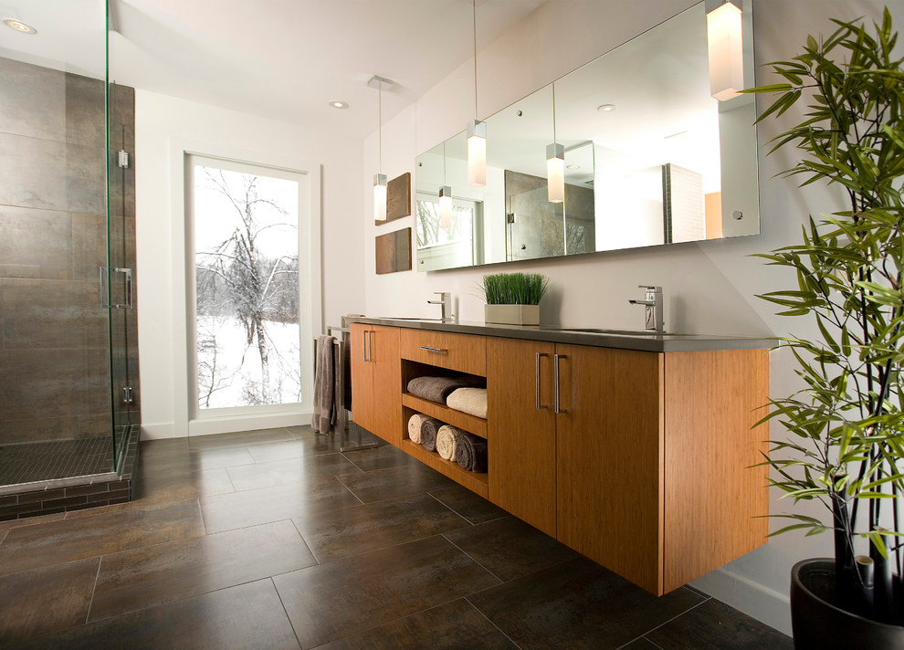 Modelo de cuarto de baño contemporáneo con lavabo bajoencimera, armarios con paneles lisos, puertas de armario de madera oscura, ducha esquinera y baldosas y/o azulejos grises