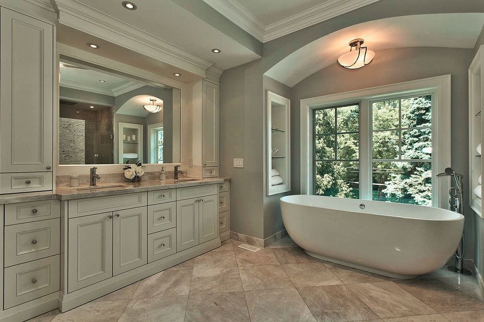 Inspiration for a large classic ensuite bathroom in Toronto with a submerged sink, white cabinets, marble worktops, a freestanding bath, grey tiles, stone tiles, grey walls, marble flooring, beaded cabinets, a built-in shower and a one-piece toilet.