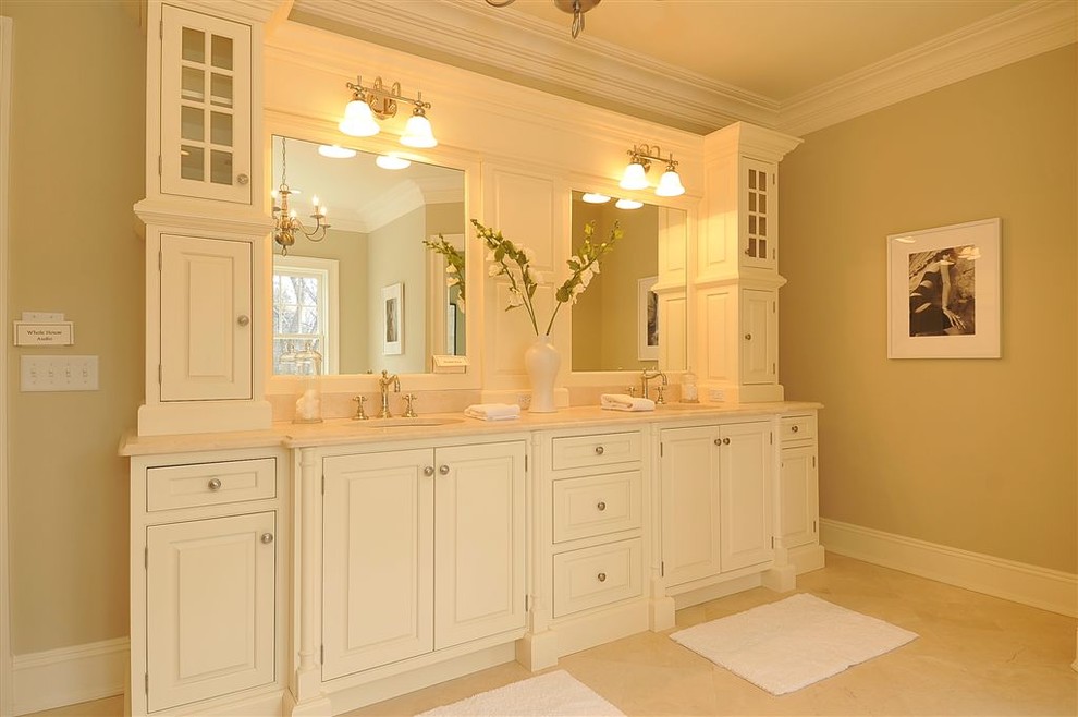 Réalisation d'une salle de bain principale tradition de taille moyenne avec un placard avec porte à panneau surélevé, des portes de placard blanches, un sol en marbre, un lavabo encastré et un plan de toilette en marbre.