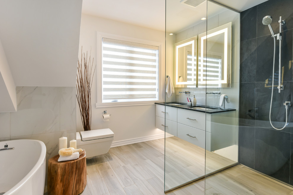 Mid-sized trendy master white tile and porcelain tile porcelain tile bathroom photo in Montreal with flat-panel cabinets, white cabinets, a wall-mount toilet, white walls, an undermount sink and solid surface countertops