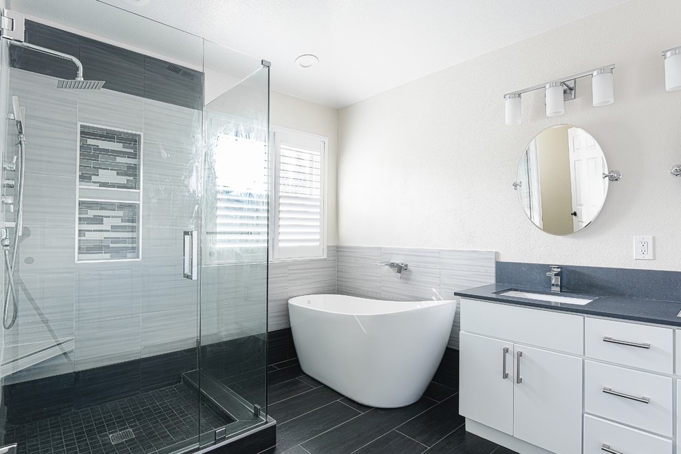 Idéer för ett stort modernt grå en-suite badrum, med vita skåp, ett undermonterad handfat, släta luckor, ett fristående badkar, en öppen dusch, en toalettstol med separat cisternkåpa, grå kakel, porslinskakel, flerfärgade väggar, klinkergolv i porslin, bänkskiva i kvartsit, grått golv och dusch med gångjärnsdörr