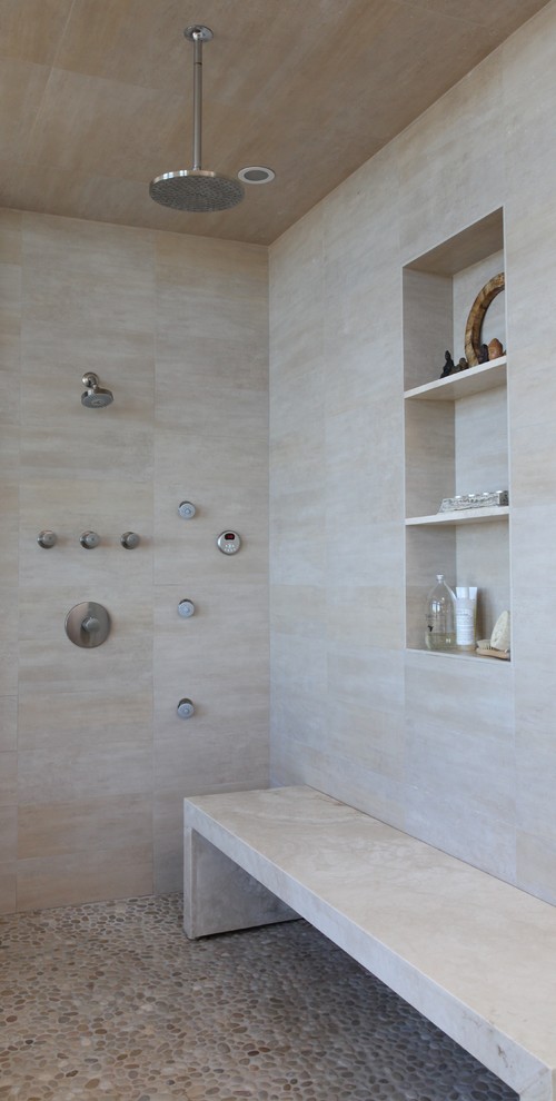 Immagine di una stanza da bagno minimal con piastrelle beige, pavimento con piastrelle di ciottoli, nicchia e panca da doccia