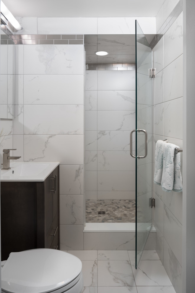 This is an example of a small contemporary ensuite bathroom in Newark with dark wood cabinets, an alcove shower, a one-piece toilet, white tiles, porcelain tiles, white walls, porcelain flooring, an integrated sink, glass worktops, white floors, a hinged door, white worktops and flat-panel cabinets.