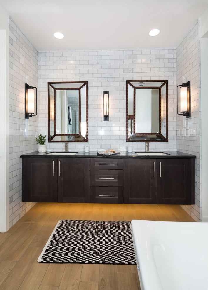 Cette image montre une salle de bain principale rustique en bois foncé de taille moyenne avec un placard à porte shaker, une baignoire indépendante, une douche d'angle, WC à poser, un carrelage noir, un carrelage de pierre, un mur blanc, un sol en bois brun, un lavabo encastré et un plan de toilette en quartz modifié.