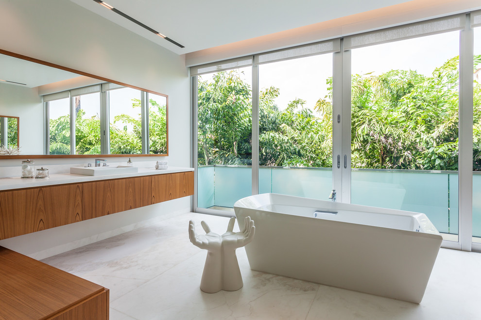 Example of a trendy freestanding bathtub design in Miami with a drop-in sink, flat-panel cabinets, medium tone wood cabinets and white walls