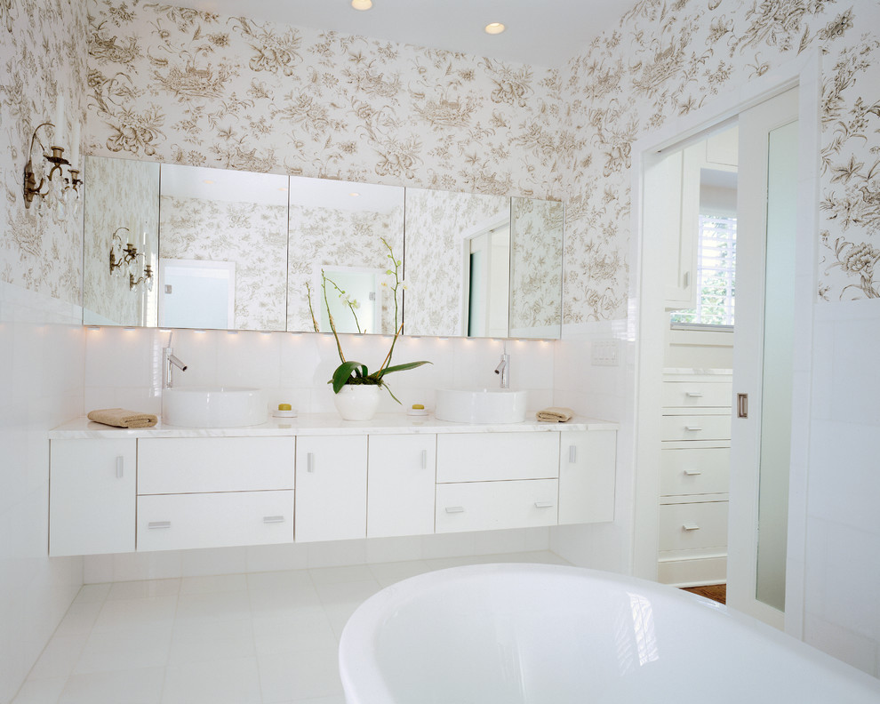 Foto de cuarto de baño moderno con lavabo sobreencimera, armarios con paneles lisos, puertas de armario blancas y bañera exenta