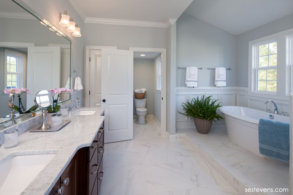 Exemple d'une salle de bain principale chic en bois foncé de taille moyenne avec un lavabo posé, un placard à porte plane, un plan de toilette en marbre, une baignoire indépendante, WC à poser, un carrelage blanc, un mur gris et un sol en linoléum.