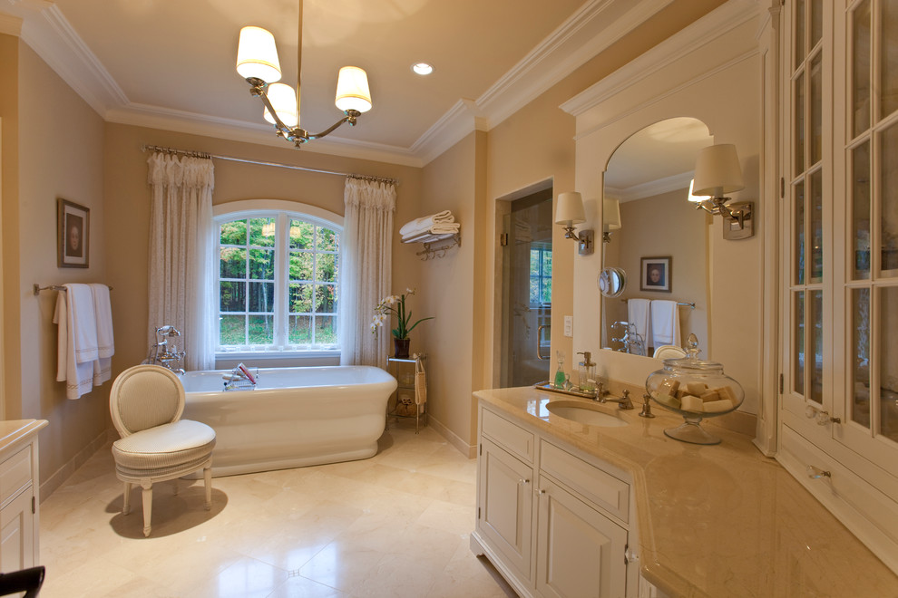 Diseño de cuarto de baño clásico grande con lavabo bajoencimera, armarios con rebordes decorativos, encimera de mármol, bañera exenta, ducha a ras de suelo y suelo de madera en tonos medios