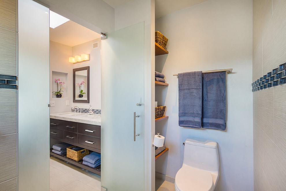 Cette photo montre une petite salle de bain tendance en bois foncé avec un placard en trompe-l'oeil, un espace douche bain, WC à poser, un carrelage gris, des carreaux de porcelaine, un mur gris, un sol en carrelage de porcelaine, un lavabo encastré, un plan de toilette en marbre et un sol beige.