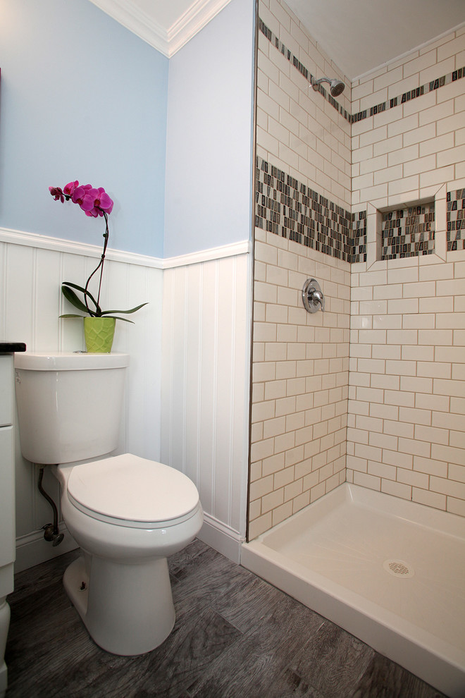 Photo of a small beach style ensuite bathroom in New York with recessed-panel cabinets, white cabinets, an alcove shower, a two-piece toilet, grey tiles, ceramic tiles, blue walls, ceramic flooring, an integrated sink and granite worktops.