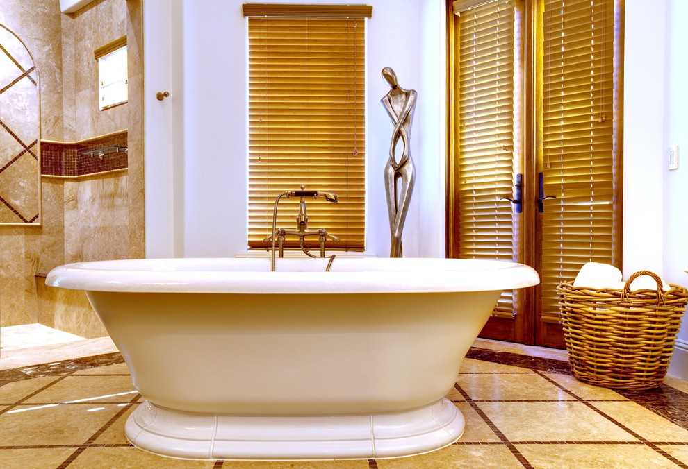 Exempel på ett medelhavsstil badrum, med ett fristående badkar och beige kakel