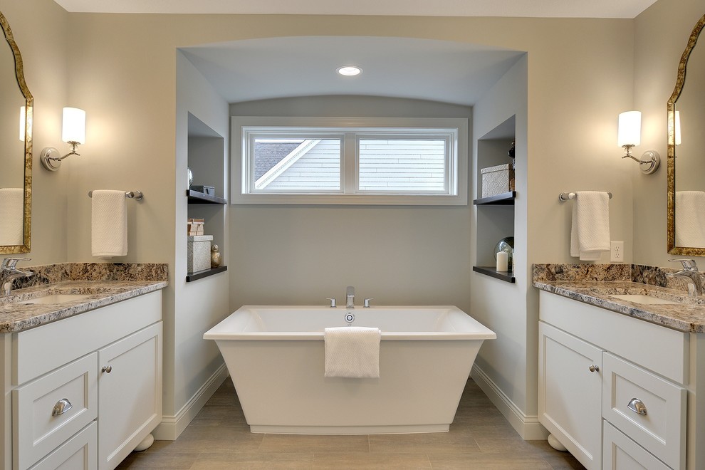 Photo of a large classic ensuite bathroom in Minneapolis with a submerged sink, recessed-panel cabinets, white cabinets, a freestanding bath, an alcove shower, a one-piece toilet, brown tiles, porcelain tiles, white walls and porcelain flooring.