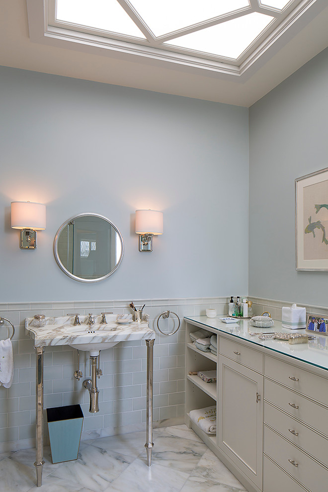 Foto på ett vintage en-suite badrum, med ett konsol handfat, luckor med infälld panel, vita skåp, bänkskiva i glas, en hörndusch, en toalettstol med hel cisternkåpa, blå kakel, keramikplattor, blå väggar och marmorgolv