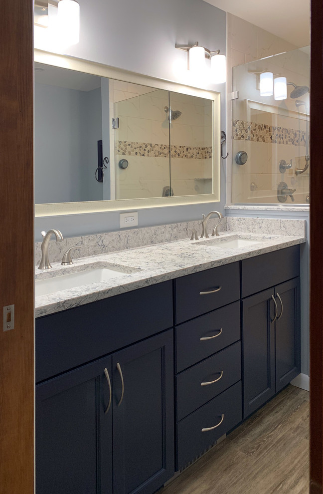 This is an example of a medium sized classic ensuite bathroom in Philadelphia with shaker cabinets, blue cabinets, a one-piece toilet, white tiles, marble tiles, blue walls, porcelain flooring, a submerged sink, engineered stone worktops, brown floors, a hinged door and white worktops.