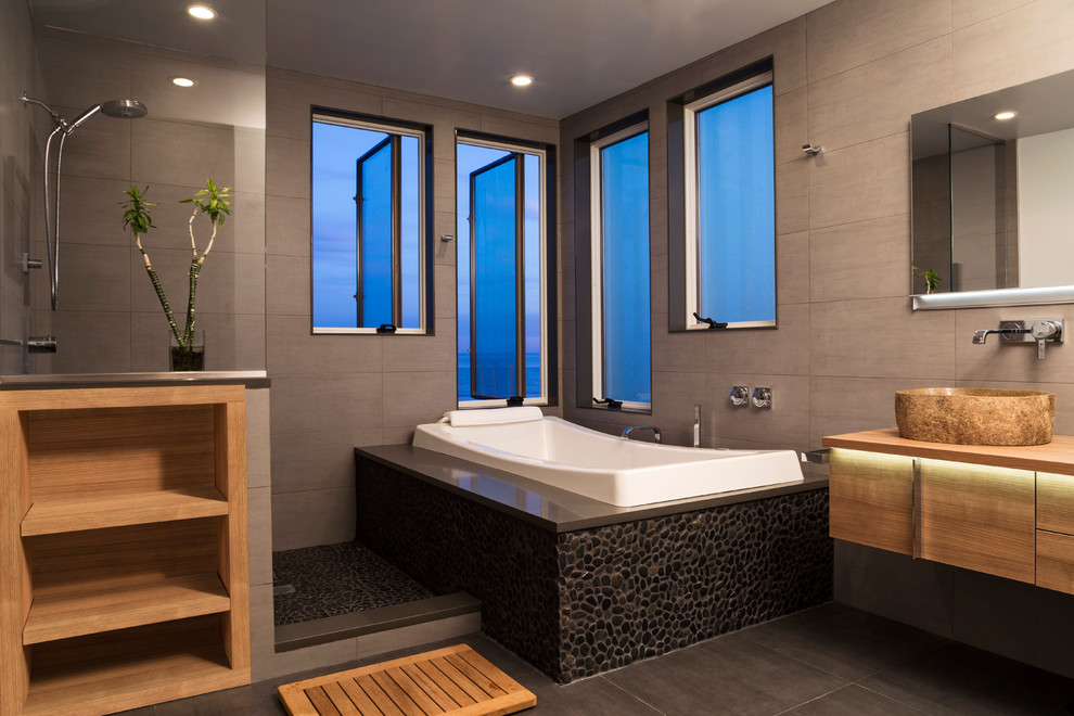 Example of a trendy drop-in bathtub design in New York with a vessel sink