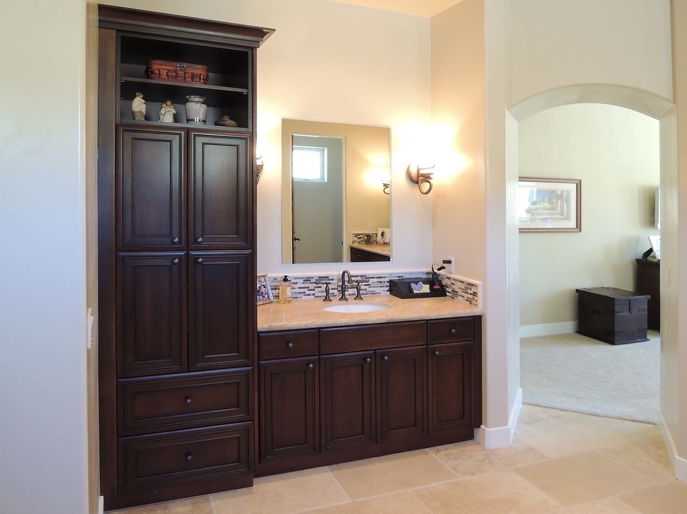 Klassisk inredning av ett stort en-suite badrum, med ett undermonterad handfat, luckor med upphöjd panel, skåp i mörkt trä, granitbänkskiva, ett fristående badkar, flerfärgad kakel, stickkakel, vita väggar och travertin golv
