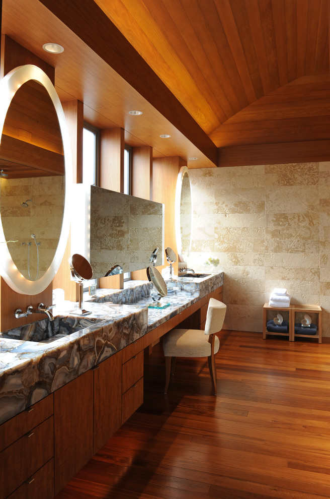 Inspiration pour une grande salle de bain principale design en bois brun avec un lavabo intégré, un placard à porte plane, un carrelage beige, un carrelage de pierre, un mur beige et un sol en bois brun.